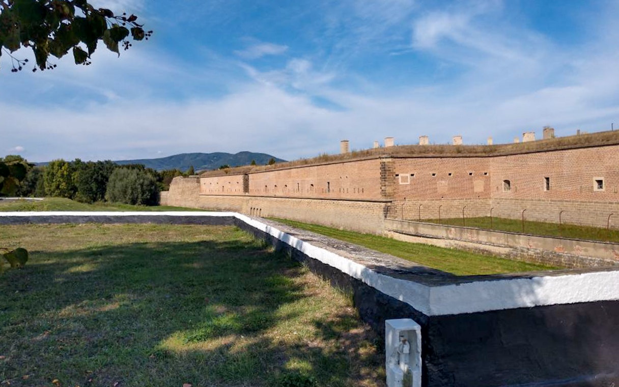 Terezin Concentration Camp brick walls and grassy area under a blue sky, viewed on a tour from Prague.