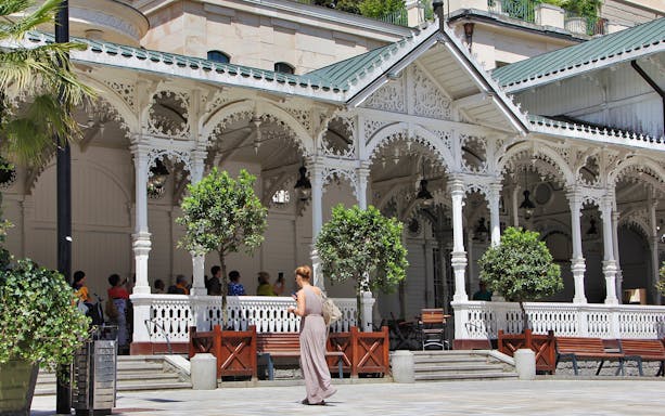 Elegant colonnade in Karlovy Vary with visitors exploring the historic architecture.