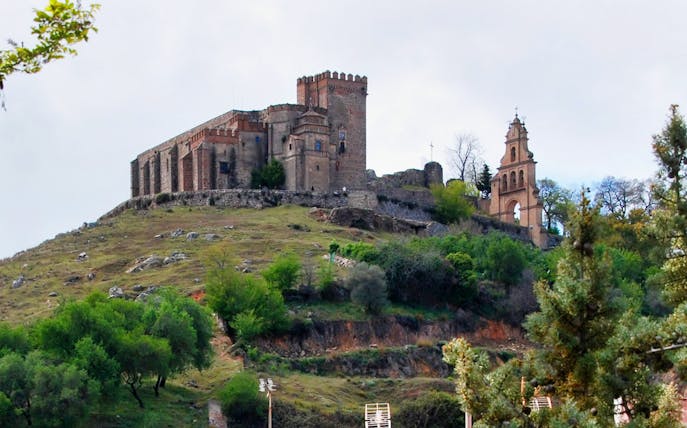 Aracena Castle on a hilltop surrounded by greenery, part of Aracena & Riotinto Day Trip from Seville.