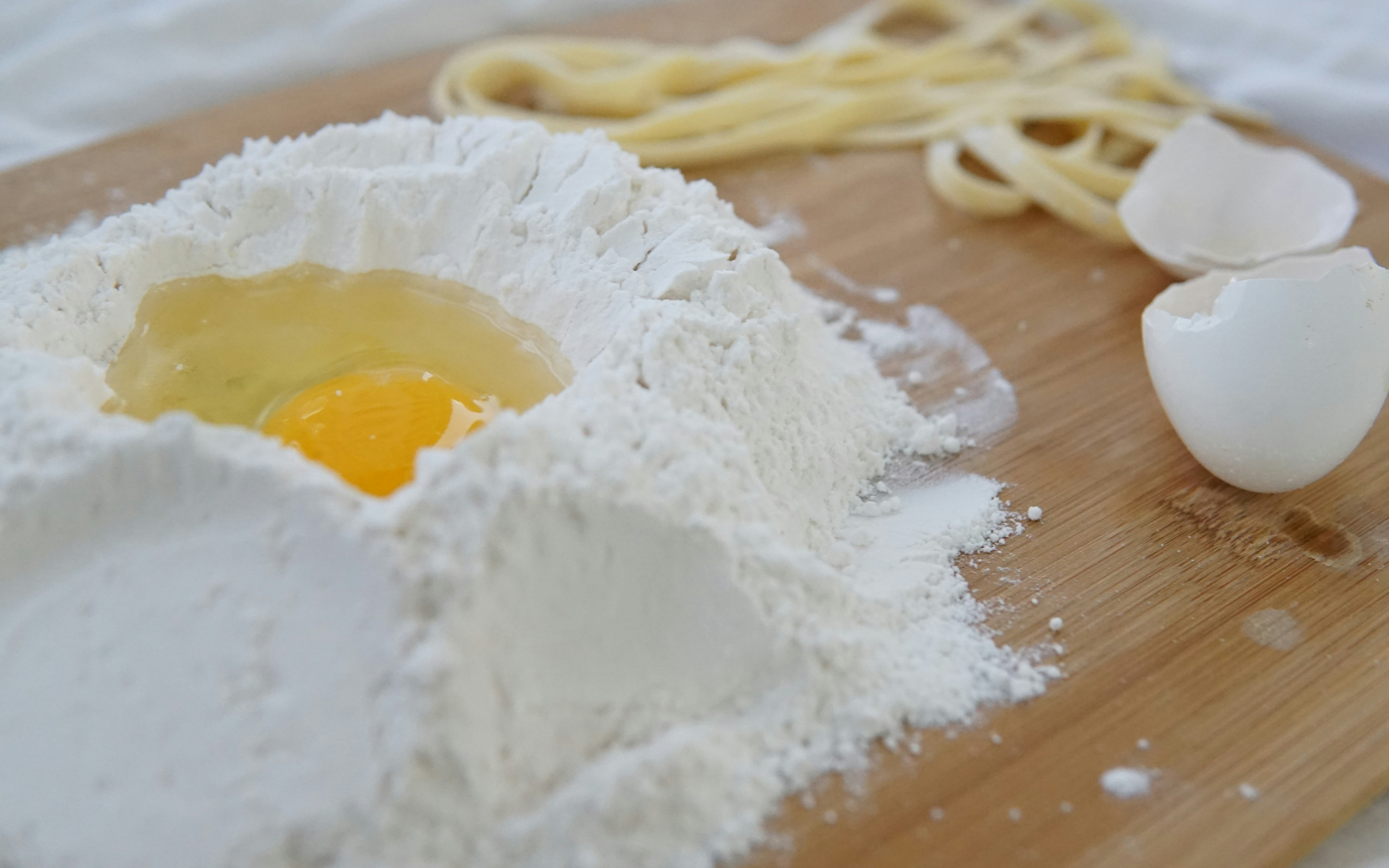 Flour and egg on a wooden board for pasta making class with Italian chefs.