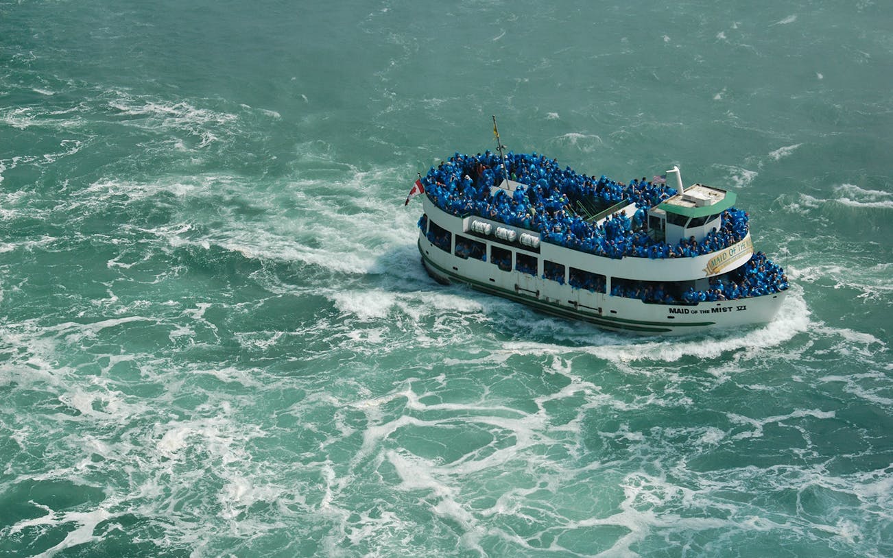 Maid of the Mist boat with tourists in blue ponchos near Niagara Falls.