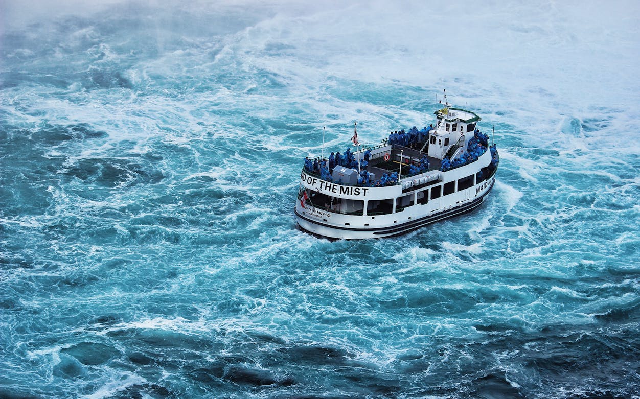 Maid of the Mist boat navigating near Niagara Falls with passengers in blue ponchos.