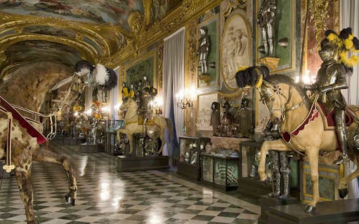 Knights in armor on horseback in the Royal Palace of Turin's ornate hall.