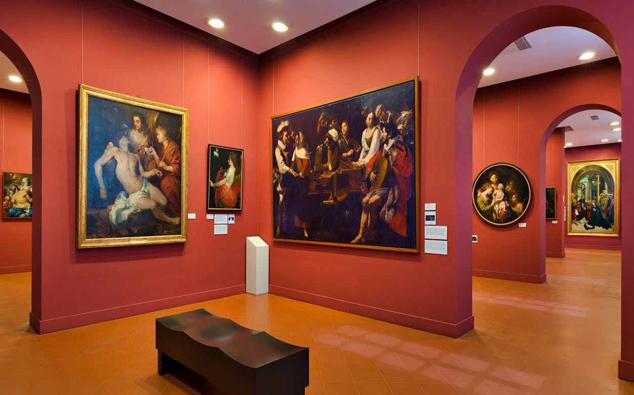 Albertina Gallery exhibition room with classical paintings on red walls.