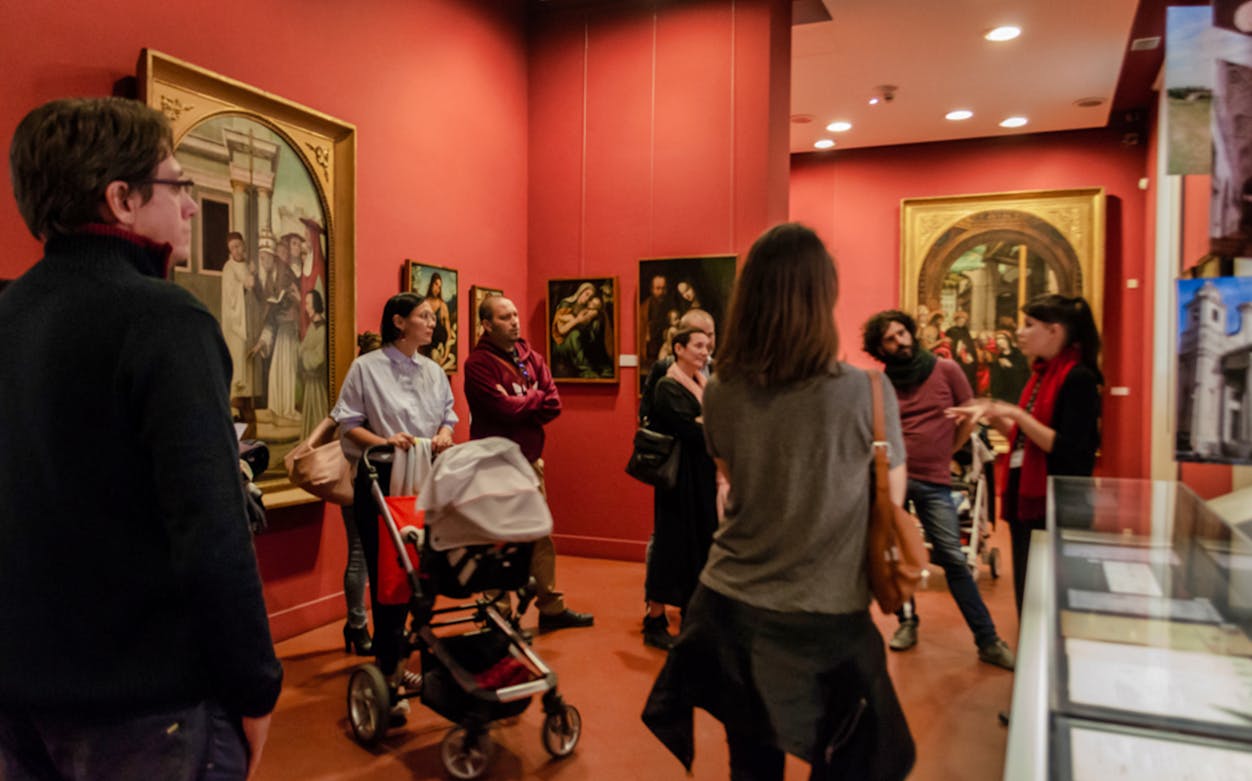 Visitors listening to a guide in the Albertina Gallery, Vienna, surrounded by classic paintings.