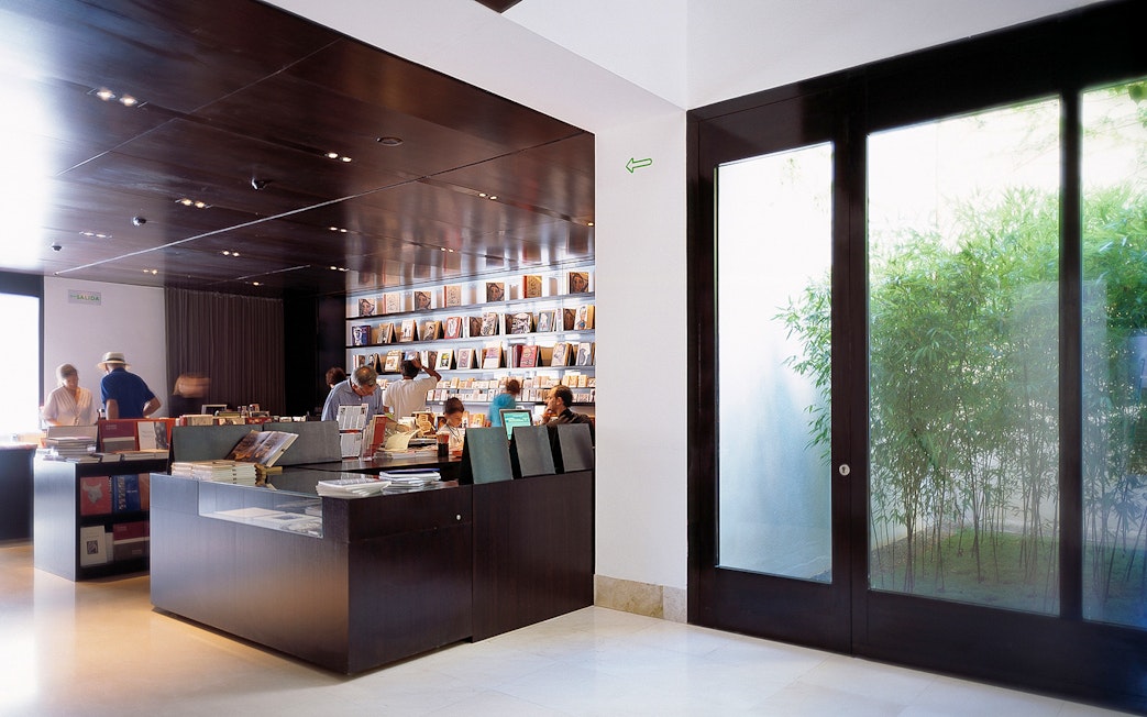 Visitors browsing books at Picasso Museum gift shop in Malaga, Spain.