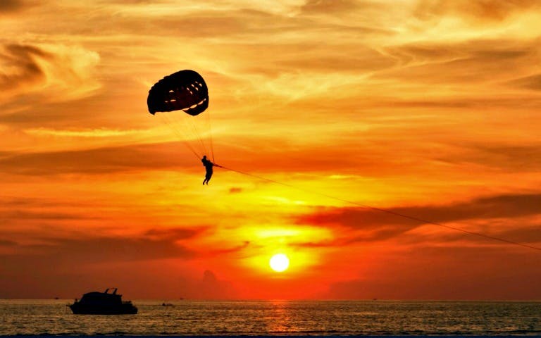 Parasailing at sunset over Waikiki during a Royal Dinner Cruise.