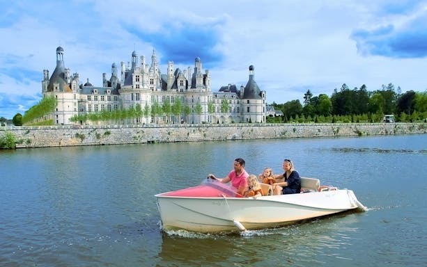 Family boating near Chambord Castle, France.