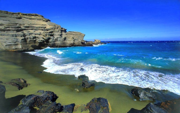 Green sand beach with turquoise waves at Papakōlea, Hawaii, part of Atlantis Combo tour.