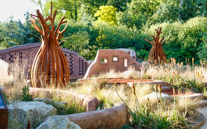 Loire Valley garden with unique sculptures and patterned walls surrounded by greenery.