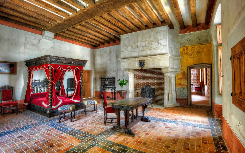 Interior of a historic room with a canopy bed and fireplace at Amboise Castle, France.