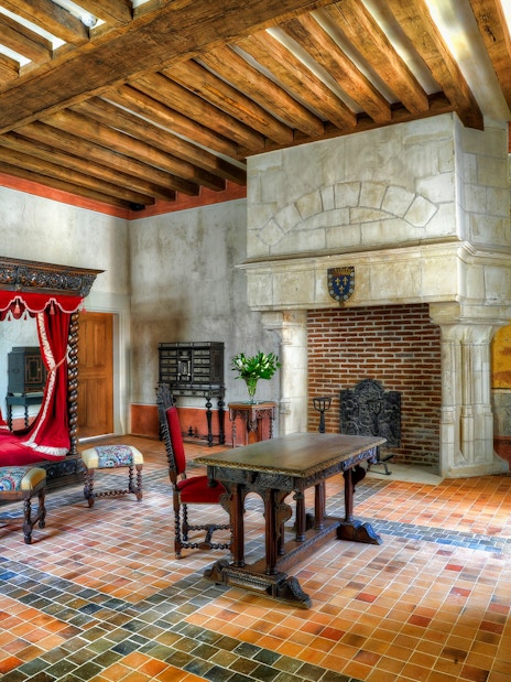 Interior of a historic room with a canopy bed and fireplace at Amboise Castle, France.