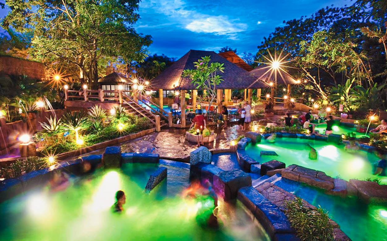 Lost World Hot Springs Night Park with illuminated pools and visitors enjoying the warm water.