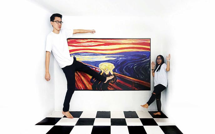 Visitors interacting with a 3D art piece at Penang 3D Trick Art Museum.