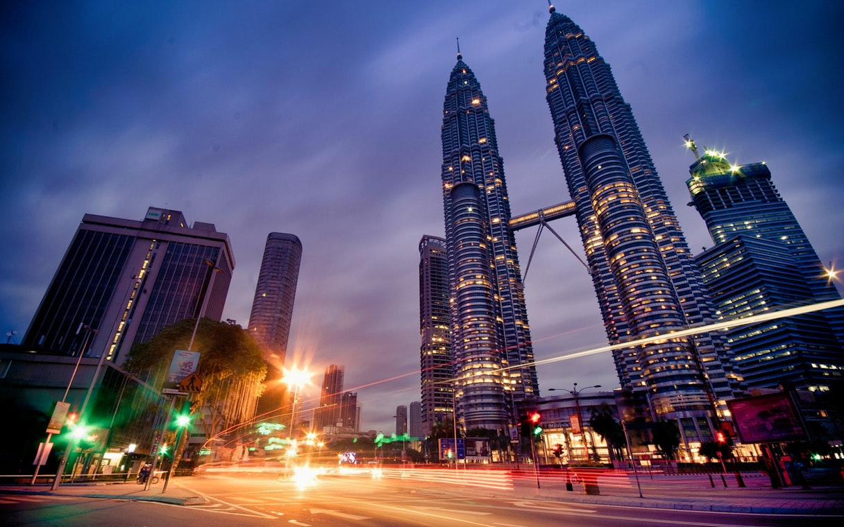 Petronas Twin Towers illuminated at dusk, Kuala Lumpur cityscape.