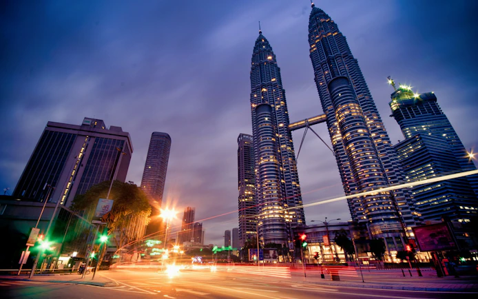 Petronas Twin Towers illuminated at dusk, Kuala Lumpur cityscape.