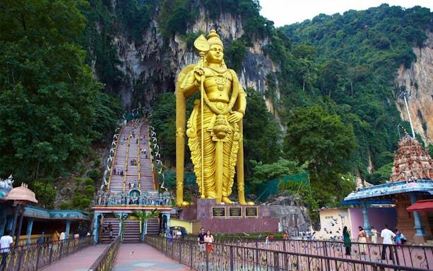 Batu Caves entrance with golden Lord Murugan statue and colorful steps, Malaysia.