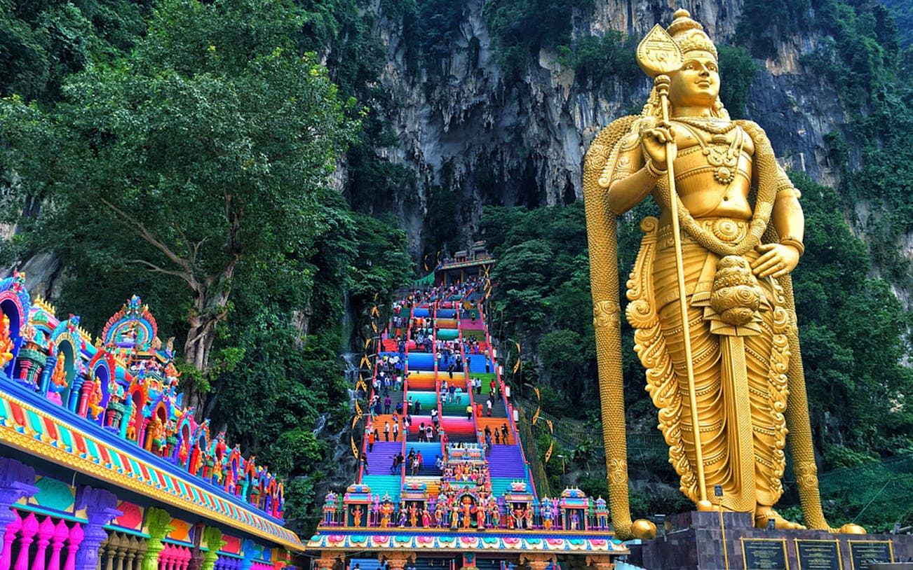 Batu Caves entrance with colorful steps and large statue in Kuala Lumpur, Malaysia.