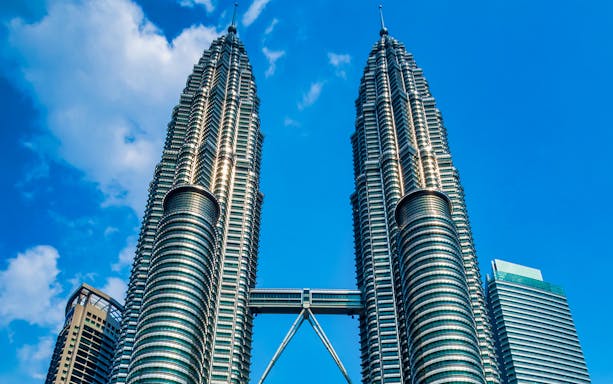 Petronas Twin Towers in Kuala Lumpur against a blue sky.