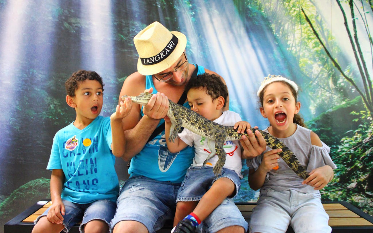 Family holding a small crocodile at Crocodile Adventureland Langkawi.