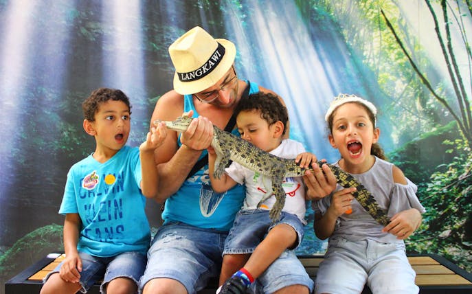 Family holding a small crocodile at Crocodile Adventureland Langkawi.