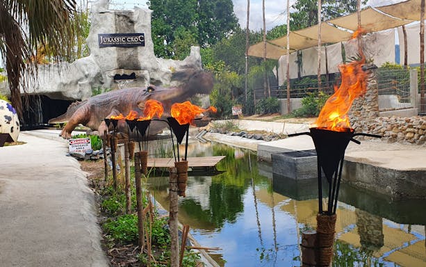 Crocodile Adventureland Langkawi entrance with flaming torches and dinosaur sculpture.