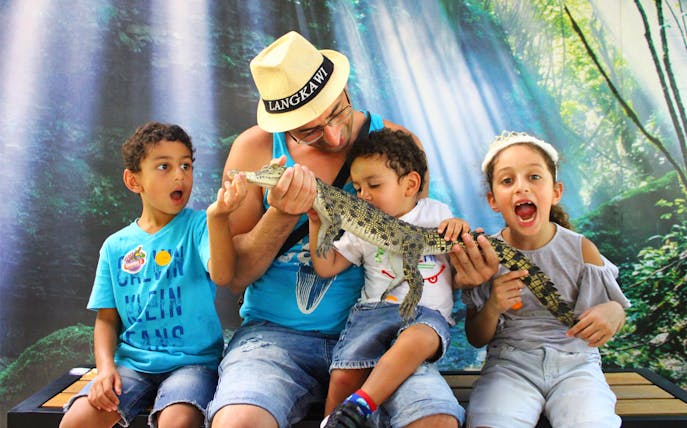 Family holding a baby crocodile at Crocodile Adventureland Langkawi.
