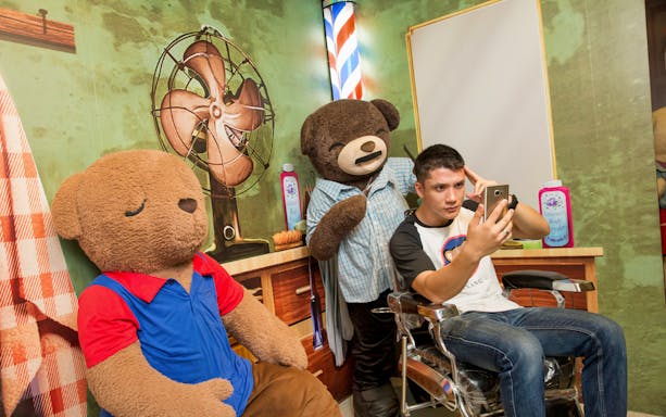Man taking selfie with teddy bears at Penang TeddyVille Museum.