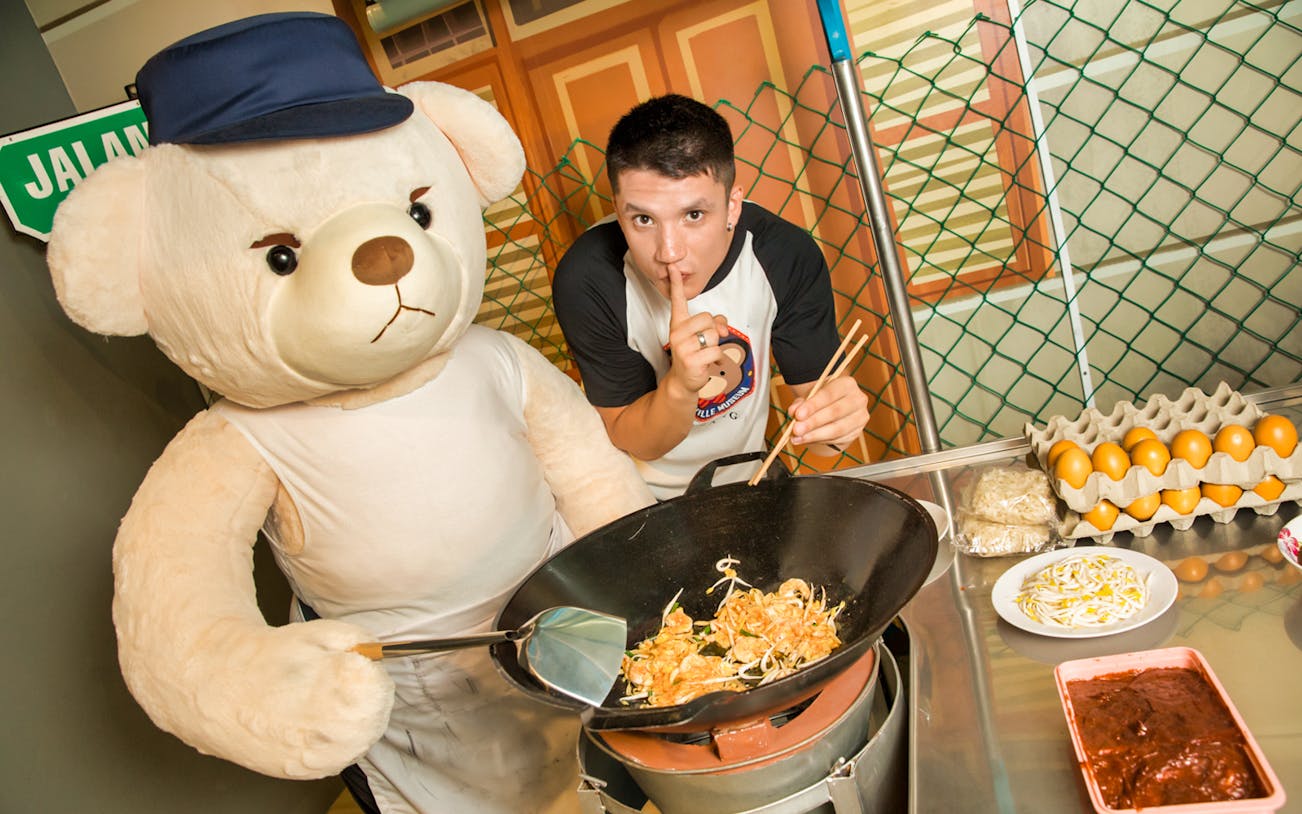 Teddy bear cooking noodles with a person at Penang TeddyVille Museum.
