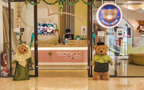 Entrance of Penang TeddyVille Museum with teddy bear mascots in traditional attire.