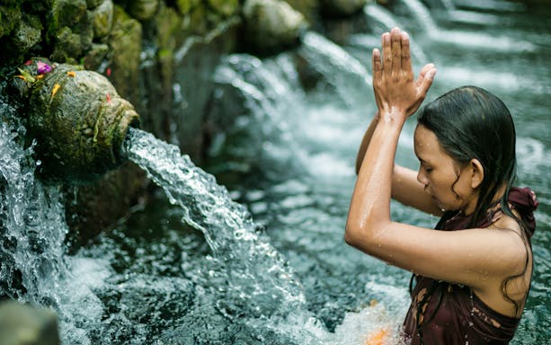 Person performing a ritual at a water temple in Bali, part of Kintamani Small Group Tour.