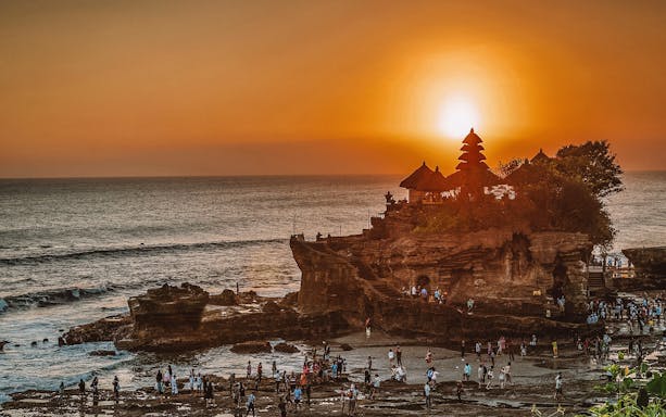 Tanah Lot temple at sunset with visitors, East Bali tour.