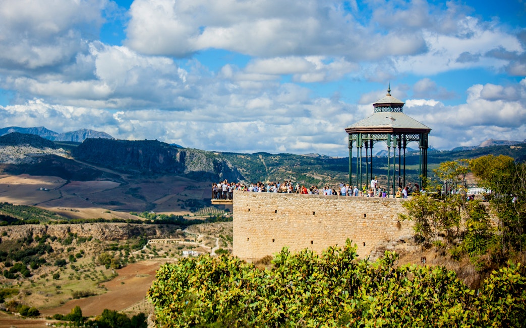 Scenic view of Ronda's Mirador de Ronda with tourists, overlooking the Andalusian landscape on a day trip from Málaga.