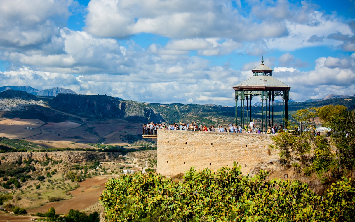 Scenic view of Ronda's Mirador de Ronda with tourists, overlooking the Andalusian landscape on a day trip from Málaga.