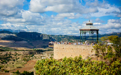 Scenic view of Ronda's Mirador de Ronda with tourists, overlooking the Andalusian landscape on a day trip from Málaga.
