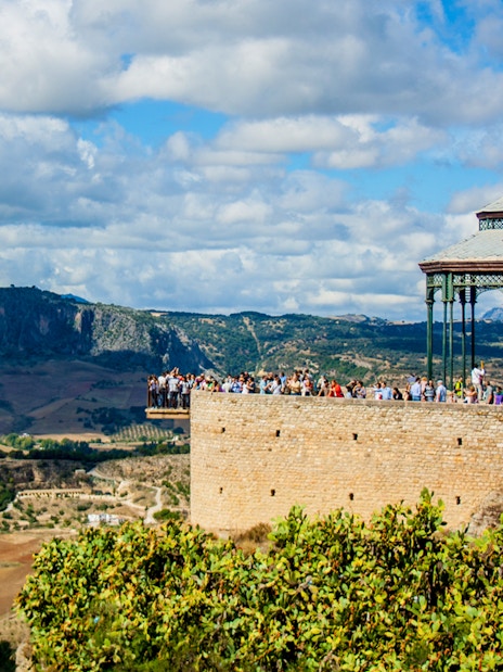 Scenic view of Ronda's Mirador de Ronda with tourists, overlooking the Andalusian landscape on a day trip from Málaga.