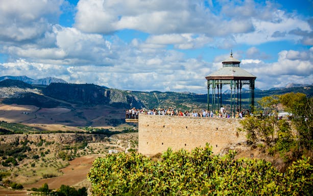 Scenic view of Ronda's Mirador de Ronda with tourists, overlooking the Andalusian landscape on a day trip from Málaga.