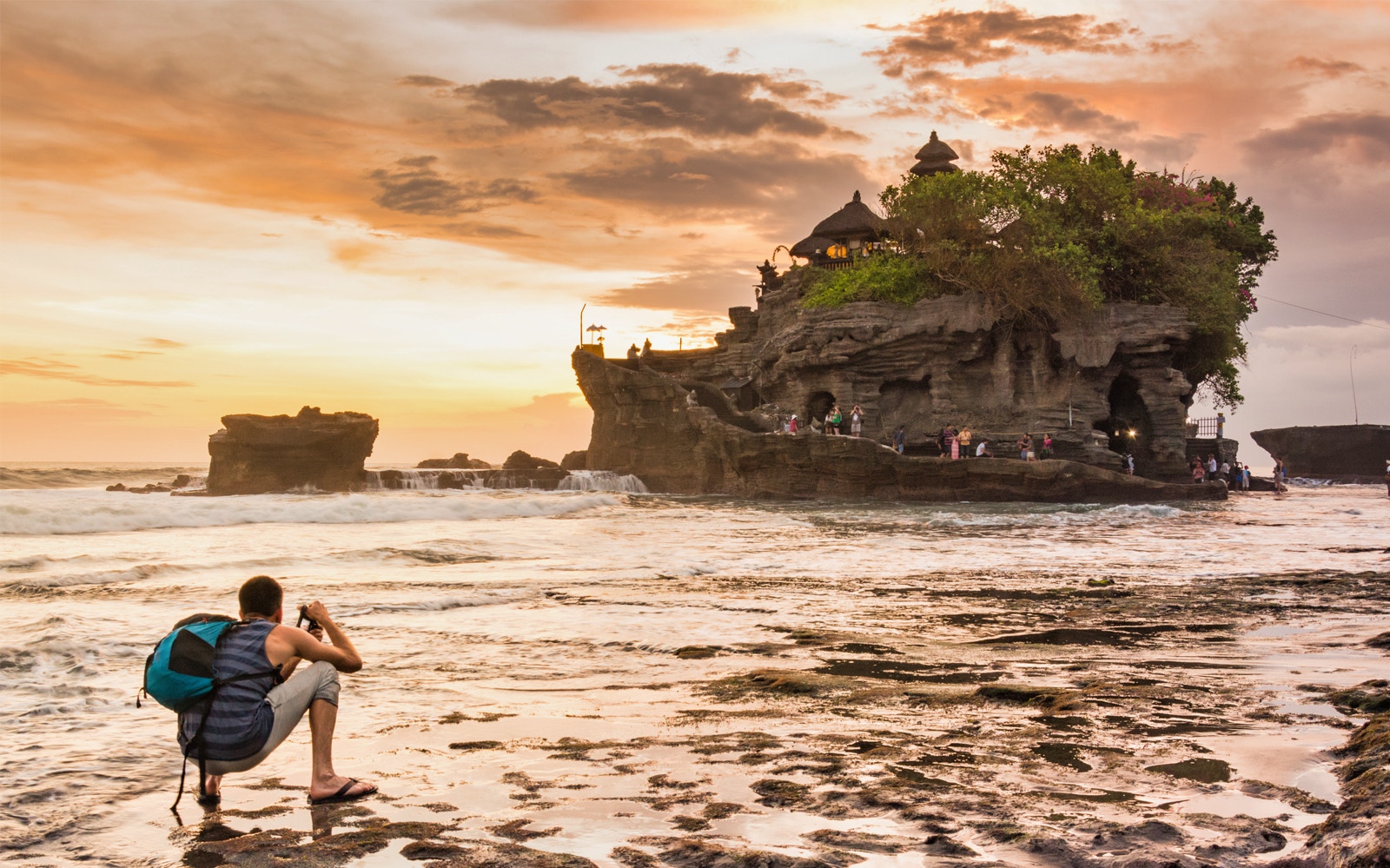 Tanah Lot Temple at sunset with tourists on a small group tour, Bali.