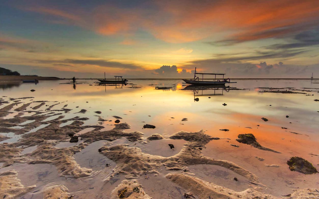 Sanur Beach at sunrise with boats on the water, Bali bike tour.