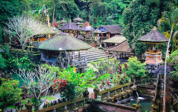 Tropical temple complex with thatched roofs and lush greenery in Bali, Indonesia.