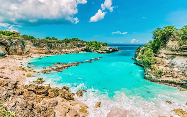 Blue Lagoon Bali with turquoise waters and rocky cliffs, ideal for snorkeling tours.