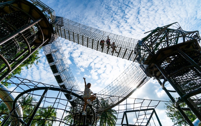 Children climbing rope structures at Nestopia Singapore against a blue sky.