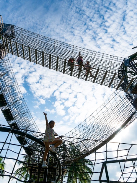 Children climbing rope structures at Nestopia Singapore against a blue sky.