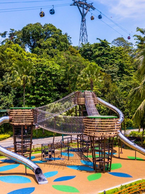 Adventure playground with slides and rope bridges at Nestopia Singapore, surrounded by lush greenery.