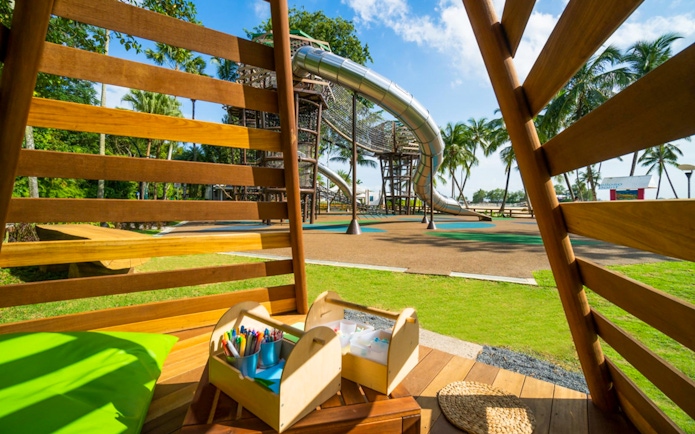 Playground with slides and climbing structures at Nestopia Singapore, view from wooden seating area.