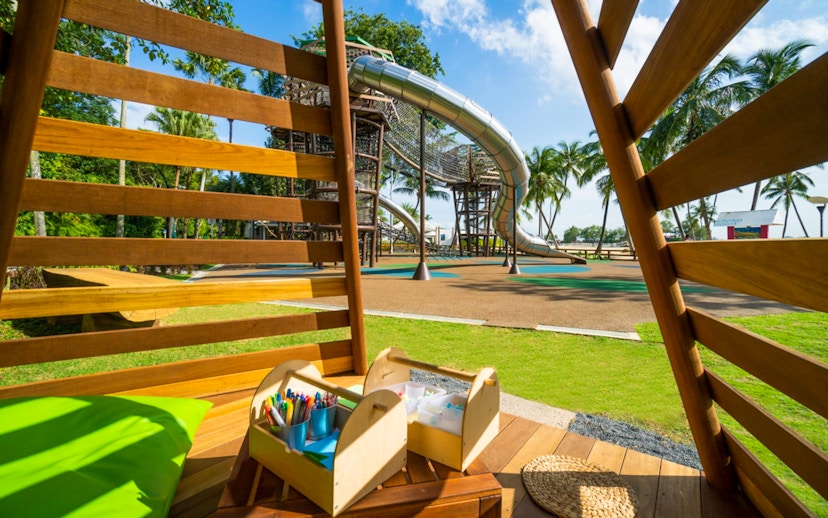 Playground with slides and climbing structures at Nestopia Singapore, view from wooden seating area.