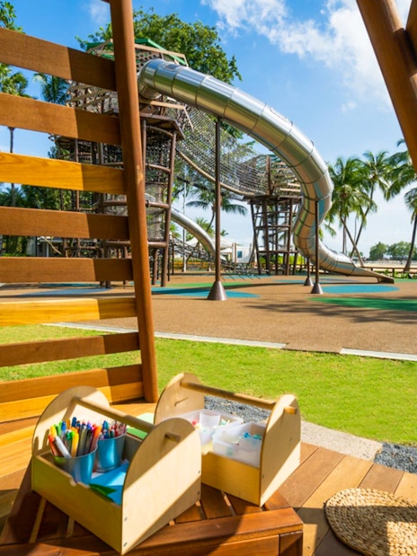Playground with slides and climbing structures at Nestopia Singapore, view from wooden seating area.