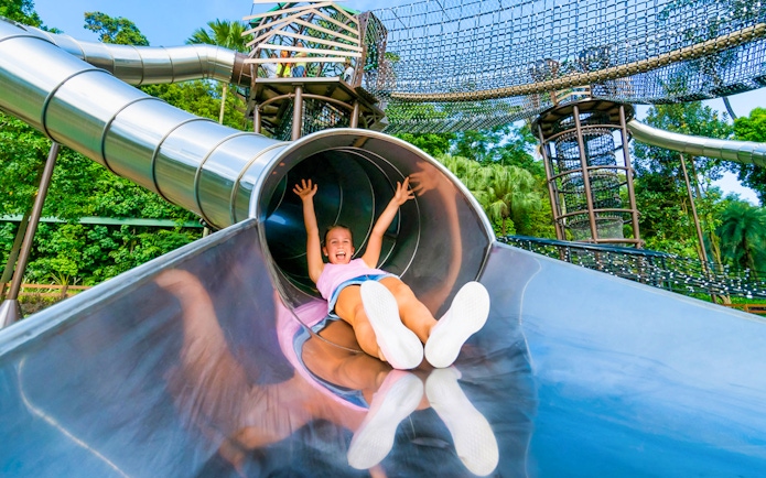 Child sliding down a metal slide at Nestopia Singapore playground.