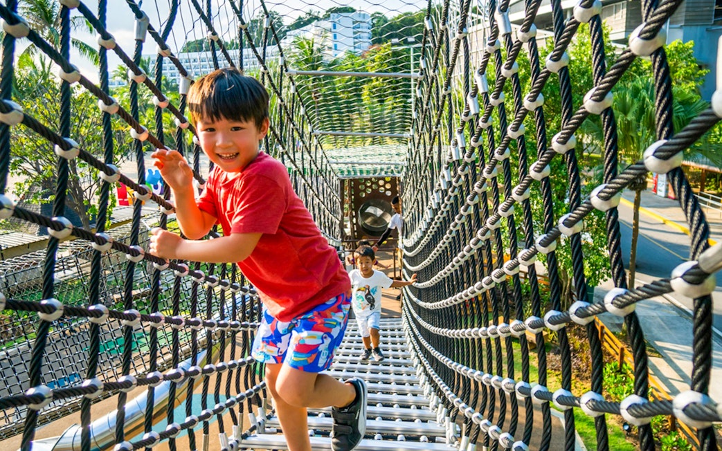 Children playing on a rope bridge at Nestopia Singapore.