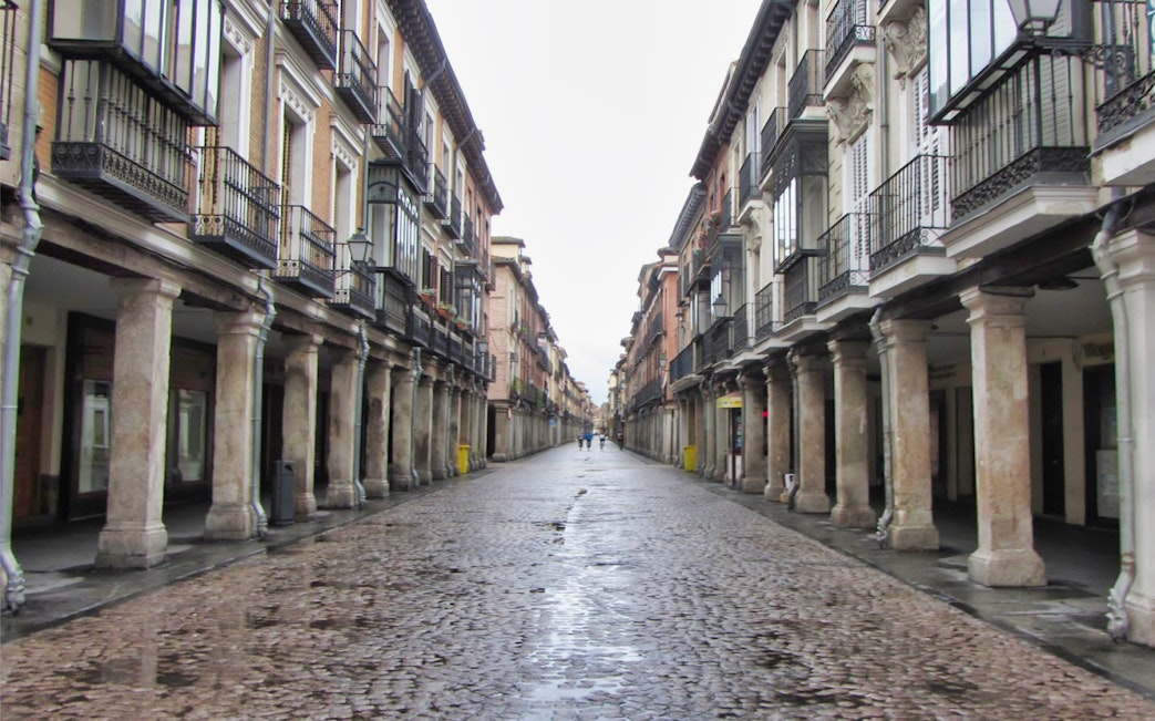 Calle Mayor in Alcala de Henares with historic colonnades and cobblestone street.